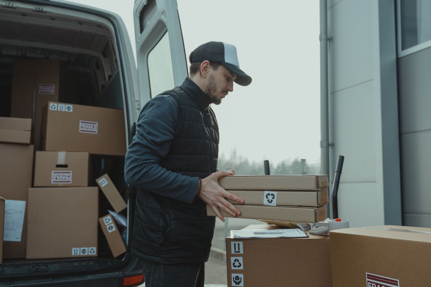 Delivery worker checking paperwork while handling parcels
