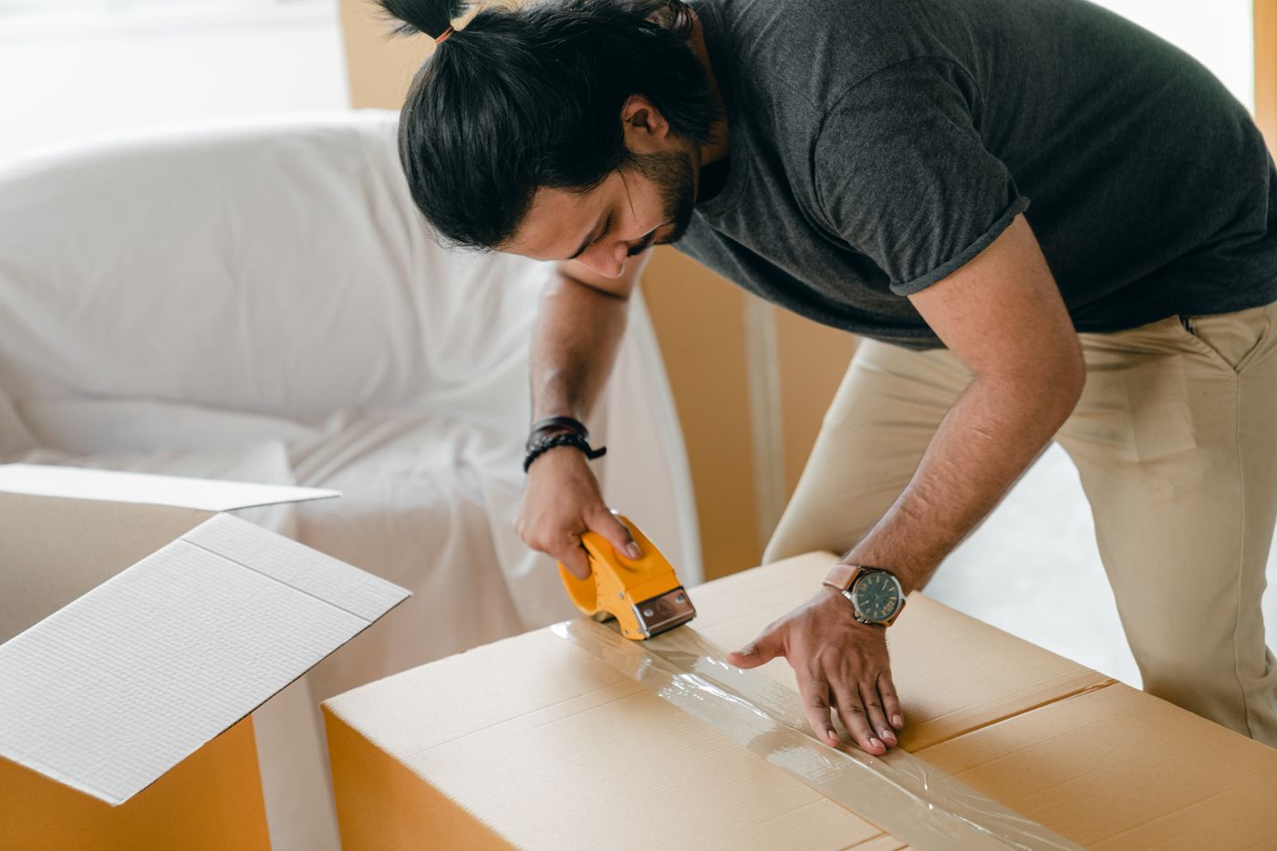 Hands sealing a cardboard box with packing tape